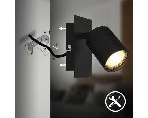 Schéma de montage d'un spot mural noir avec support mural, vis, câble, tête de lampe éclairée et symbole pour le montage.