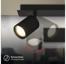 Spot orientable noir avec boîtier nervuré, illustration de la fonction de pivotement de la tête de lampe.