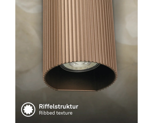 Vue détaillée d'un luminaire cylindrique avec une structure de surface nervurée et une source lumineuse intégrée.