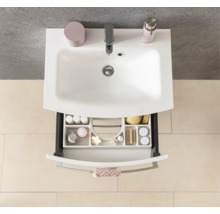 Vue de dessus d'un lavabo blanc avec robinet et un tiroir ouvert avec un organisateur clair pour les accessoires de salle de bains.