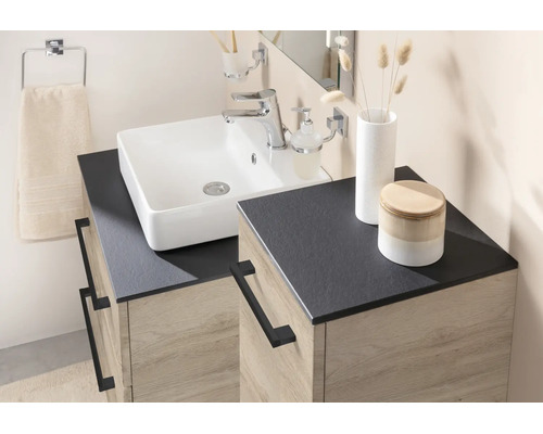 Modernes Badezimmer mit weißem Aufsatzwaschbecken, dunkler Arbeitsplatte und Unterschrank in Eichenoptik mit schwarzen Metallgriffen.