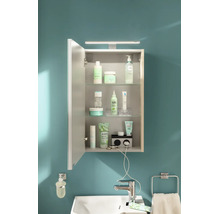 Armoire de toilette lumineuse et organisée avec éclairage LED, étagères en verre et prises intégrées au-dessus d'un lavabo blanc.
