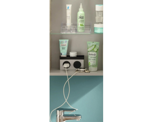 Armoire de toilette organisée avec des produits cosmétiques, un bloc de prises avec un câble de chargement pour une montre connectée et un robinet.