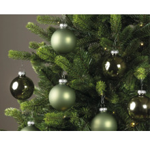 Boules de Noël de différentes nuances de vert, mates et brillantes, suspendues à un sapin de Noël vert.