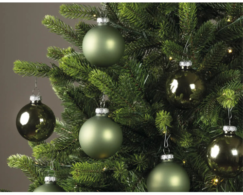 Boules de Noël de différentes nuances de vert, mates et brillantes, suspendues à un sapin de Noël vert.