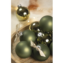 Boules de Noël vertes en versions mates et brillantes avec capuchons argentés et nœuds décoratifs sur un plateau en bois.