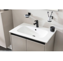 Lavabo moderne avec vasque céramique blanche, robinetterie noire, meuble bas beige et accessoires muraux assortis dans la salle de bains.