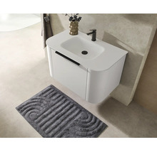 Meuble sous-vasque moderne suspendu avec vasque intégrée, robinetterie noire et tapis de bain assorti dans une salle de bains lumineuse.