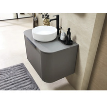 Meuble sous-vasque suspendu aux angles arrondis avec vasque à poser blanche et robinet noir dans une salle de bains moderne.