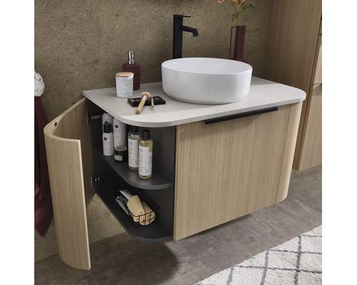 Meuble sous-vasque suspendu avec façade en bois cannelé, vasque à poser blanche et robinet noir dans une salle de bains moderne.