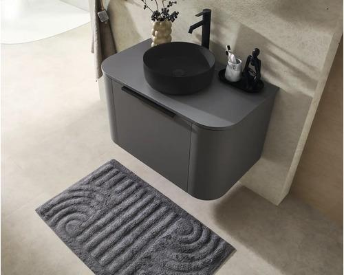Meuble sous-vasque suspendu moderne gris foncé avec une vasque à poser noire et un robinet haut sur un carrelage beige.