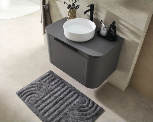 Meuble sous-vasque suspendu moderne en gris foncé avec vasque à poser blanche, robinet noir et tapis de bain gris foncé.
