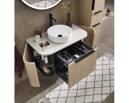 Meuble sous-vasque moderne aspect bois avec vasque à poser blanche, robinet noir et tiroir ouvert avec organiseur.