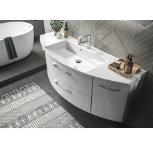 Modernes, helles Badezimmer mit geschwungenem Waschtisch, zwei Schubladen und Armatur. Im Hintergrund freistehende Badewanne und Wandfliesen.