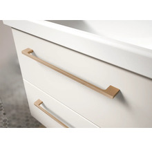 Gros plan d'un meuble sous-lavabo blanc avec deux tiroirs et de longues poignées métalliques de couleur cuivre.