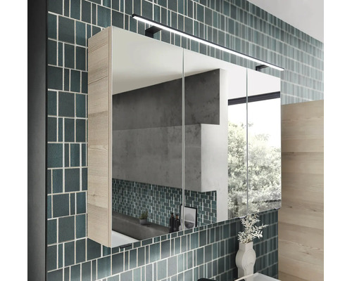 Armoire de toilette moderne à 3 portes avec éclairage LED et aspect bois sur un mur carrelé dans une salle de bains lumineuse et ordonnée.