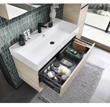 Meuble de salle de bains moderne avec lavabo en céramique blanche, meuble sous vasque en bois et tiroir ouvert avec compartiments de rangement.