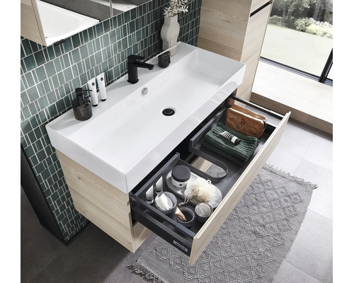 Meuble de salle de bains moderne avec lavabo en céramique blanche, meuble sous vasque en bois et tiroir ouvert avec compartiments de rangement.