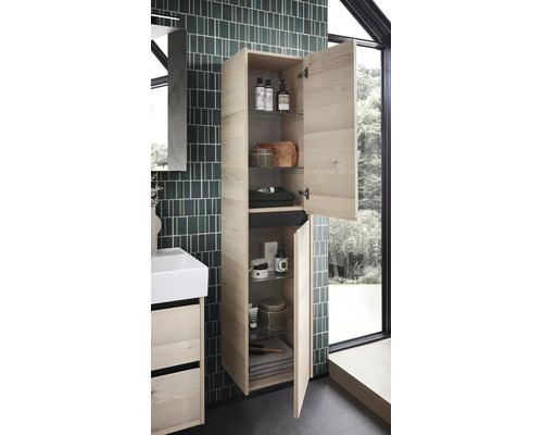 Colonne de salle de bains suspendue en aspect bois clair avec deux portes ouvertes, tablettes en verre et accessoires de bain à côté d un meuble vasque.