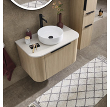 Salle de bains moderne avec meuble sous-lavabo strié aspect bois, vasque à poser blanche, robinet noir et miroir éclairé rond.