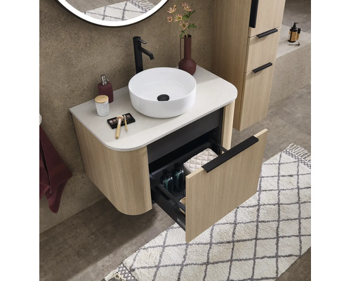Meuble sous-vasque avec vasque à poser aspect bois à structure rainurée, un tiroir ouvert, salle de bains organisée.