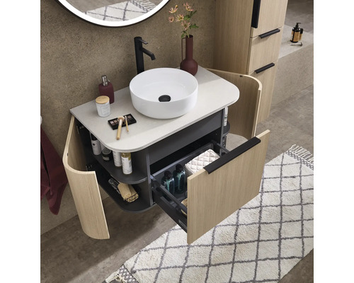 Meuble vasque moderne et organisé avec vasque ronde, tiroir ouvert, étagères latérales incurvées et façades aspect bois.