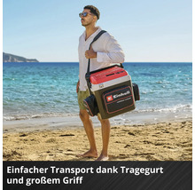 Glacière Einhell avec bandoulière, grande poignée et poche pour accessoires, portée par un homme sur une plage de sable lumineuse.