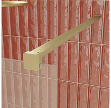 Goldfarbene, quadratische Stabilisierungsstange für eine Duschkabine aus Glas, an einer gefliesten Wand montiert.