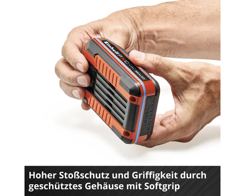 Des mains tiennent une batterie Einhell avec un boîtier Softgrip pour une protection élevée contre les chocs.