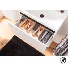 Tiroir ouvert d'un meuble sous-vasque blanc avec des boîtes de rangement en bois pour cosmétiques. (Image AI modified or generated)