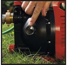 Main désignant le voyant transparent d'une pompe de jardin rouge et noire.