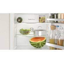Vue intérieure d'un réfrigérateur Bosch avec technologie CoolAirflow, rempli d'aliments, de récipients en verre et d'une demi-pastèque.