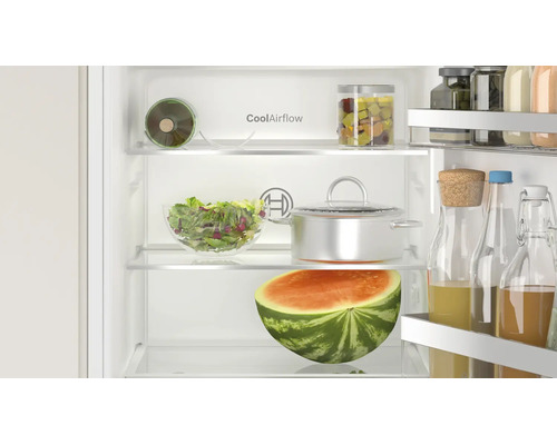 Vue intérieure d'un réfrigérateur Bosch avec technologie CoolAirflow, rempli d'aliments, de récipients en verre et d'une demi-pastèque.