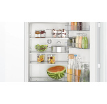 Vue intérieure d'un réfrigérateur Bosch avec clayettes en verre et balconnets remplis, ainsi qu'un système CoolAirflow pour un froid homogène.