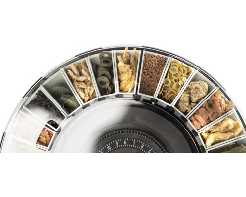 Tambour d'un distributeur de nourriture pour poissons, rempli de différents aliments comme des flocons, des comprimés et des granulés.