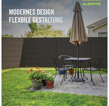 Clôture occultante Alberts moderne aspect bois foncé dans un jardin derrière un salon de jardin et des fleurs.