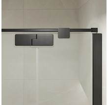 Détails de la cabine de douche avec système de porte coulissante et ferrures en métal sur une paroi en verre devant un mur carrelé.