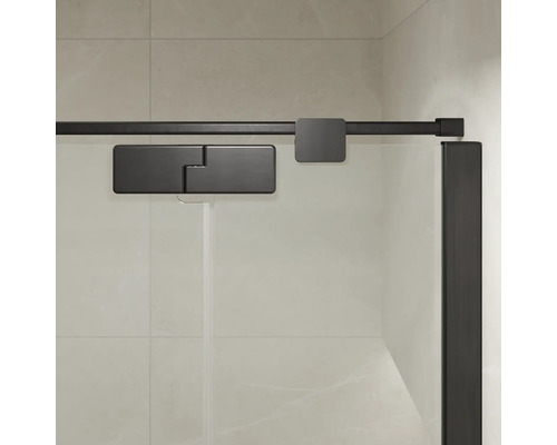 Détails de la cabine de douche avec système de porte coulissante et ferrures en métal sur une paroi en verre devant un mur carrelé.