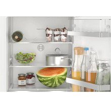 Réfrigérateur Bosch ouvert avec clayettes en verre et balconnets de porte remplis de produits alimentaires.