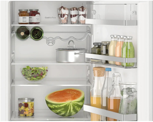 Réfrigérateur Bosch ouvert avec étagères, porte-bouteilles, balconnets de porte remplis et système CoolAirflow intégré.