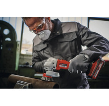 Un artisan portant des vêtements de protection utilise une meuleuse angulaire sans fil Einhell avec brosse métallique pour travailler le métal.