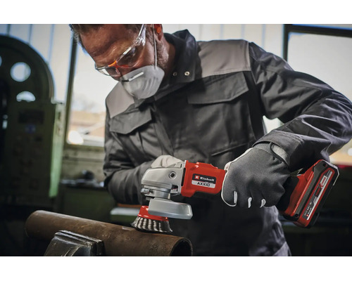 Un artisan portant des vêtements de protection utilise une meuleuse angulaire sans fil Einhell avec brosse métallique pour travailler le métal.