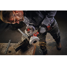 Artisan avec lunettes de protection utilise une meuleuse angulaire sans fil Einhell pour couper du métal dans un étau avec étincelles en atelier