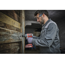 Un artisan utilise une perceuse visseuse sans fil Einhell pour visser dans un mur en bois.