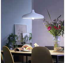 Suspension moderne au-dessus d'une table à manger dans une salle à manger lumineuse et accueillante avec un bouquet de fleurs.