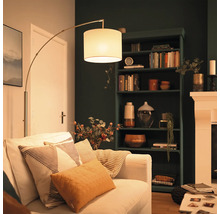 Lampadaire moderne avec abat-jour en tissu à côté d'un canapé dans un salon confortable avec une étagère sombre et une cheminée.