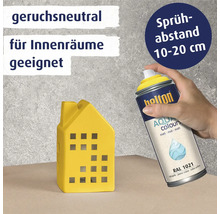 Eine Hand sprüht mit einer Belton Aqua Colors Lackspraydose auf ein gelbes Dekohaus, mit Hinweisen zu Geruchsneutralität und Sprühabstand.