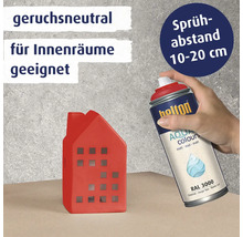 Eine Hand sprüht mit einer geruchsneutralen Belton Aqua Colours Sprühdose in Feuerrot auf ein kleines dekoratives Haus aus Keramik.
