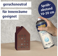 Eine Hand hält eine Sprühdose Belton Aqua Colours matt RAL 8017 über einem dekorativen Hausmodell zur Anwendung im Innenbereich.