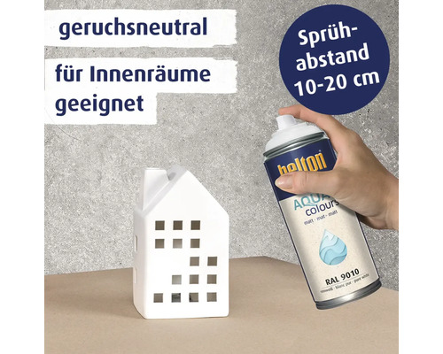 Eine Hand sprüht mit einer Belton Aqua Colours Sprühdose auf ein weißes Deko Haus. Text informiert über Geruchsneutralität und Sprühabstand.